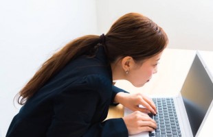 Image of woman using laptop while sitting at her desk